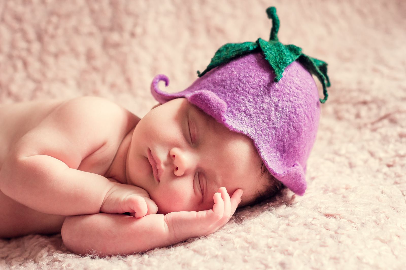 beba sa ljubičastom kapicom spava na ćebetu