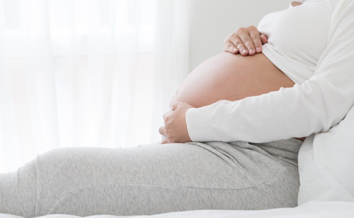 trudnica u poodmakloj trudnoći na krevetu drži ruke na stomaku