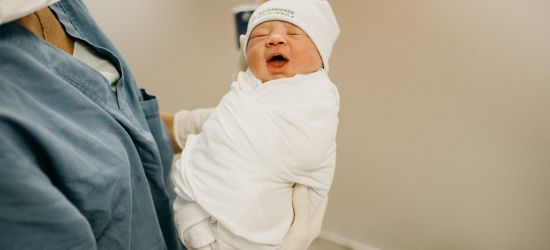 majlka drži u rukama novorođenu bebu